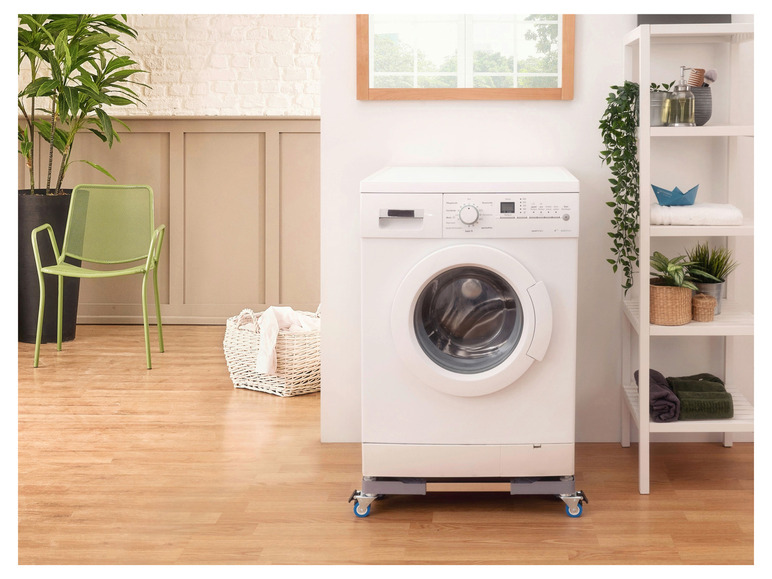 Een witte wasmachine met wielen in een moderne badkamer.