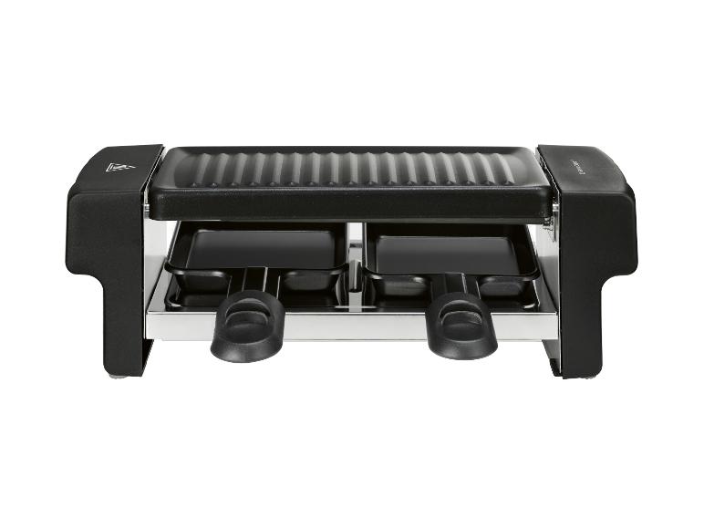 Gril à raclette noir avec deux poêles et une plaque supérieure rainurée.