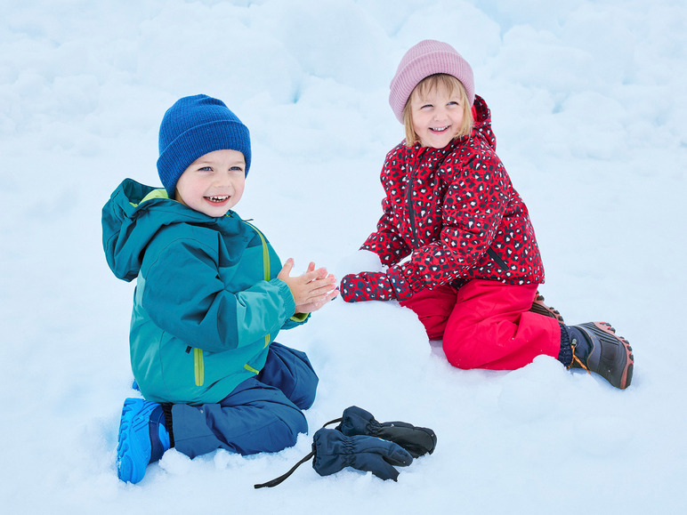 Deux enfants en vêtements d'hiver jouent dans la neige.