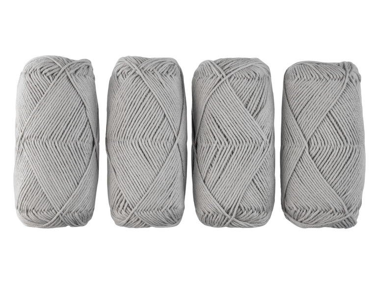 Quatre pelotes de laine grise pour tricoter ou crocheter.