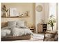 Chambre moderne avec lit beige, literie grise et décor neutre.