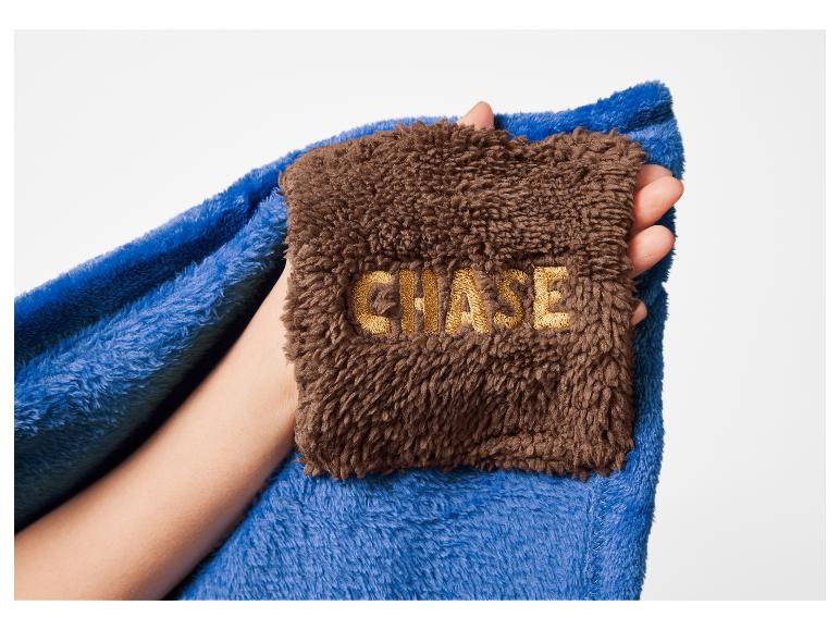 Blauwe en bruine deken met geborduurde tekst 'CHASE' in een hand