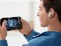 Homme en chemise en jean joue sur smartphone, portant un écouteur intra-auriculaire blanc.