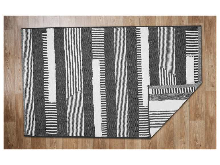 Een zwart-wit gestreept vloerkleed op een houten vloer.