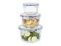 Pile de trois récipients alimentaires ronds en verre avec couvercles bleus, un rempli de salade, un de courgettes.