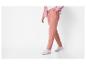 Une personne en pantalon de survêtement rose et un cardigan rose.