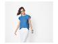 Vrouw in blauw T-shirt met ruches en witte broek, zonnebril en armbanden.