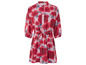 Een roze jurk met rode bloemenprint en ceintuur.