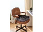 Coussin ergonomique sur une chaise de bureau en cuir marron dans un bureau à domicile.