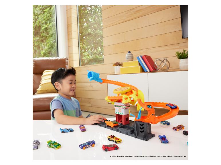 Un garçon joue avec un ensemble Hot Wheels comprenant un dragon et de nombreuses voitures.