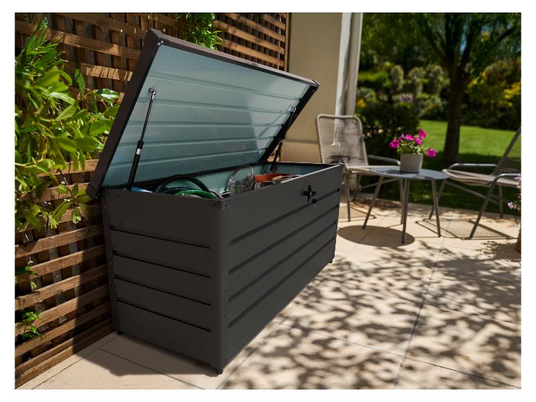 Donkergrijze buitenopbergbox met open deksel, gevuld met tuingereedschap, op een terras.