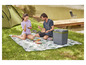 Een stel geniet van een picknick met een koelerbox op een picknickkleed.