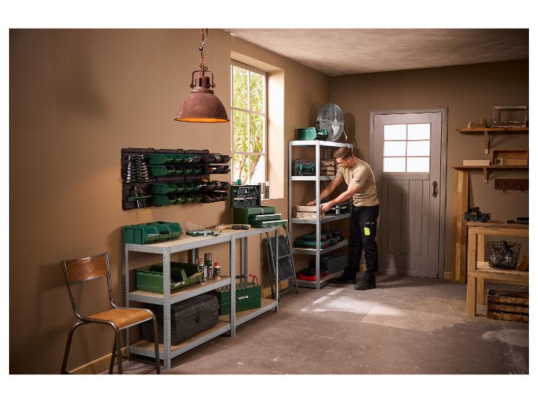 Homme organisant des outils et des boîtes de rangement dans un garage ou un atelier.