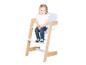 Peutermeisje zit op een witte en houten kinderstoel.