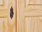 Een houten kastdeur met een decoratief messing handvat.