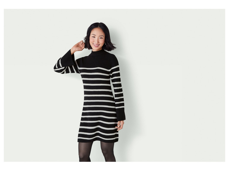 Une femme porte une robe pull à rayures noires et blanches.