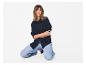 Vrouw in gestreept marineblauw overhemd en lichte jeans, knielend.