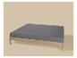 Houten bed met grijs matras op een beige achtergrond.