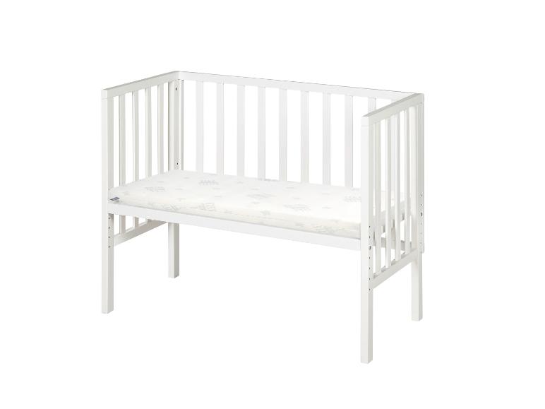 Wit babybedje met matras op een witte achtergrond.