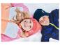 Deux enfants en vestes d'hiver colorées et bonnets sont allongés dans la neige en souriant.