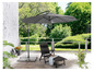 Een grijze parasol met een zwarte ligstoel op een terras.