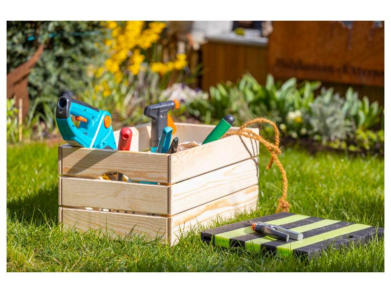 Tuingereedschap in een houten kist op het gras.