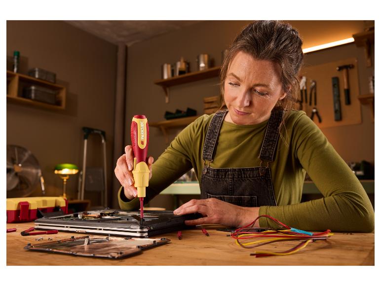 Vrouw gebruikt een Parkside schroevendraaier om een laptop te repareren op een houten bureau.