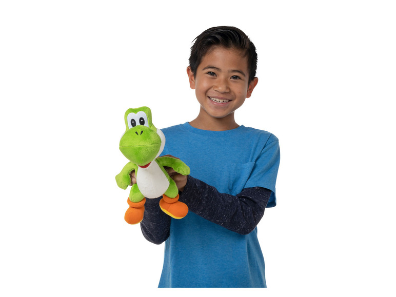 Un garçon tient un Yoshi en peluche.