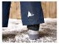 Blauwe ski broek met een driehoekig logo en witte schoenen op sneeuw.