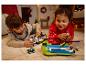 Twee kinderen spelen met LEGO-speelgoed op een tapijt in een kerstversierde kamer.