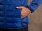 Une veste matelassée bleue avec une main dans la poche.