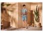 Man in overhemd met korte mouwen en denim shorts, sandalen, in een mediterrane setting.