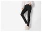 Vrouw in zwarte skinny jeans en beige sneakers.