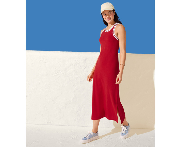 Een vrouw draagt een rode jurk met witte strepen en blauwe sneakers.