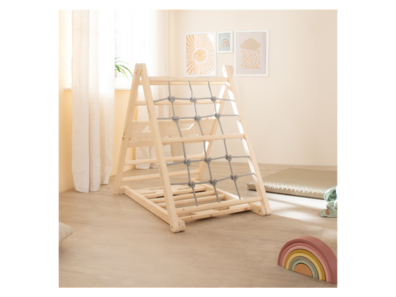 Houten klimrek voor kinderen met touwennet, naast babyspeelgoed.