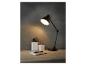 Een zwarte bureaulamp met een notitieboekje en pennen op een houten bureau.