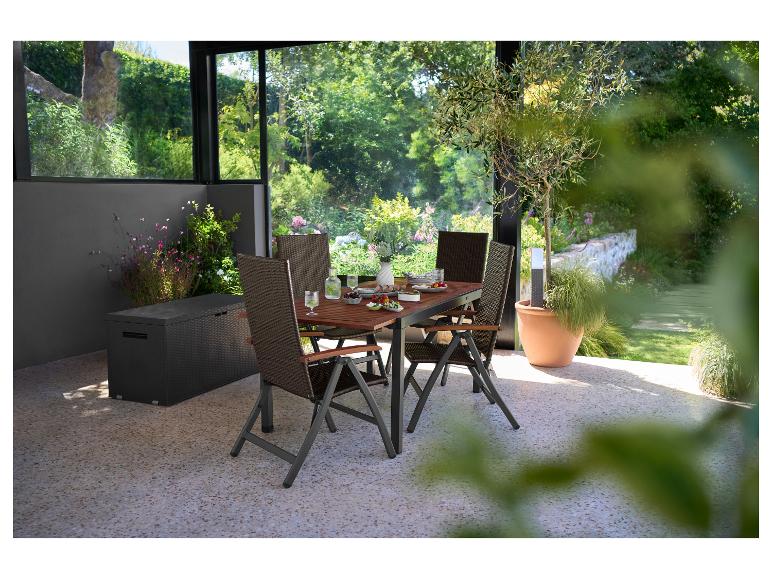 Buiten eethoek met houten tafel en opvouwbare rieten stoelen op een terras.