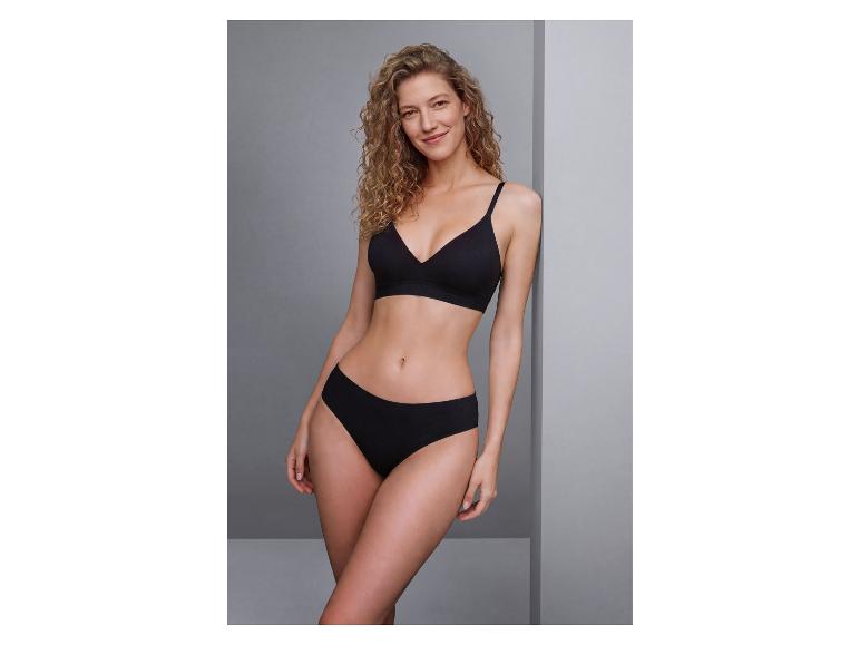Lachende vrouw met krullend haar in een zwarte beha en slip.