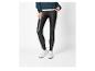 Une personne portant un pull torsadé sarcelle, des leggings noirs en similicuir et des baskets blanches.