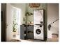 Moderne wasruimte met wasmachine en droger, grijze kasten en groene tegels.