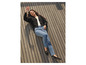 Une femme porte un cardigan noir, un jean bleu et des mocassins noirs à chaînes.