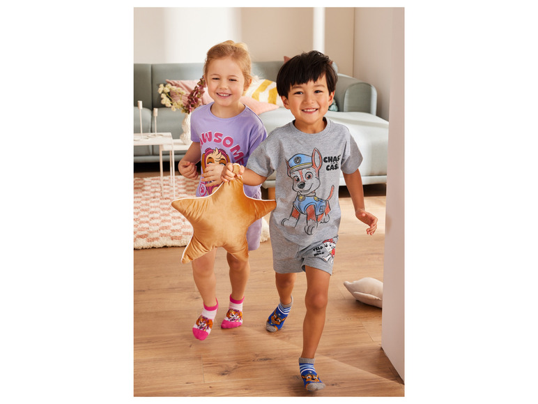 Deux enfants en pyjama et chaussettes Paw Patrol.