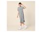 Femme en robe t-shirt grise, lunettes et baskets blanches, souriante.