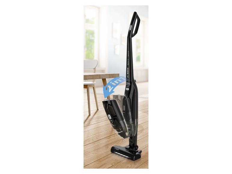 Aspirateur balai sans fil 2-en-1 noir sur un sol en bois dans une pièce lumineuse.