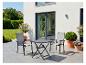 Terrasse extérieure avec une table pliante gris foncé et deux chaises assorties, entourée de plantes en pot.