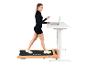 Femme sur tapis de course, travaillant sur un ordinateur portable à un bureau réglable.