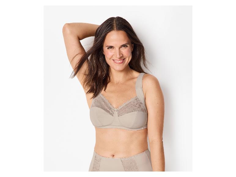 Femme souriante en soutien-gorge en dentelle beige et culotte assortie.
