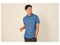 Homme en polo bleu avec logo palmier et jean foncé.