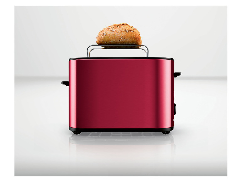 Un grille-pain rouge avec un pain sur le dessus.