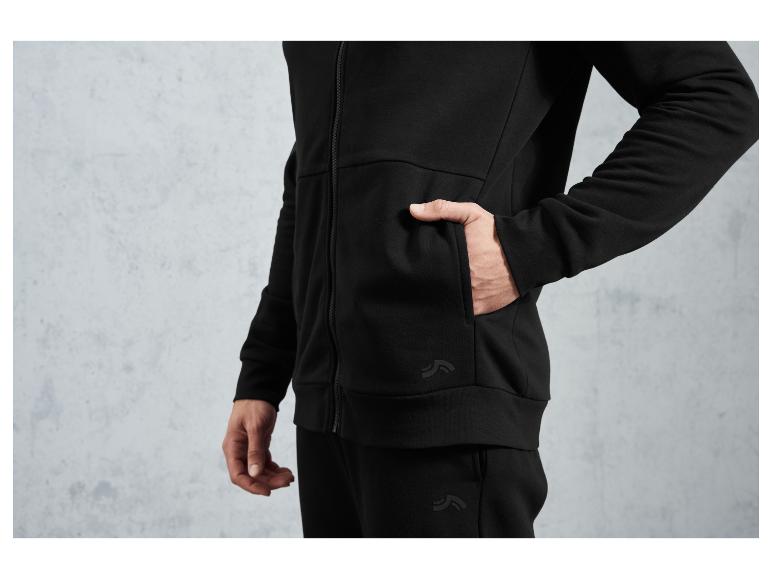 Un homme porte un sweat-shirt à capuche et un pantalon noirs de la marque 'The North Face'.